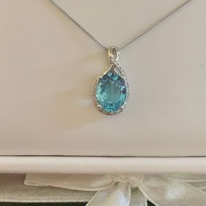 White 14 karat pendant with one 2.78 ct oval blue topaz and .13Tw Round Diamonds